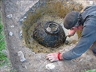 An archaeologist works to clear the clay pot discovered by Dave Crisp.