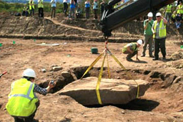 Two members of the SERF project team watch as a crane lifts a four-ton stone block that covered a well-preserved 4,000 year old tomb.